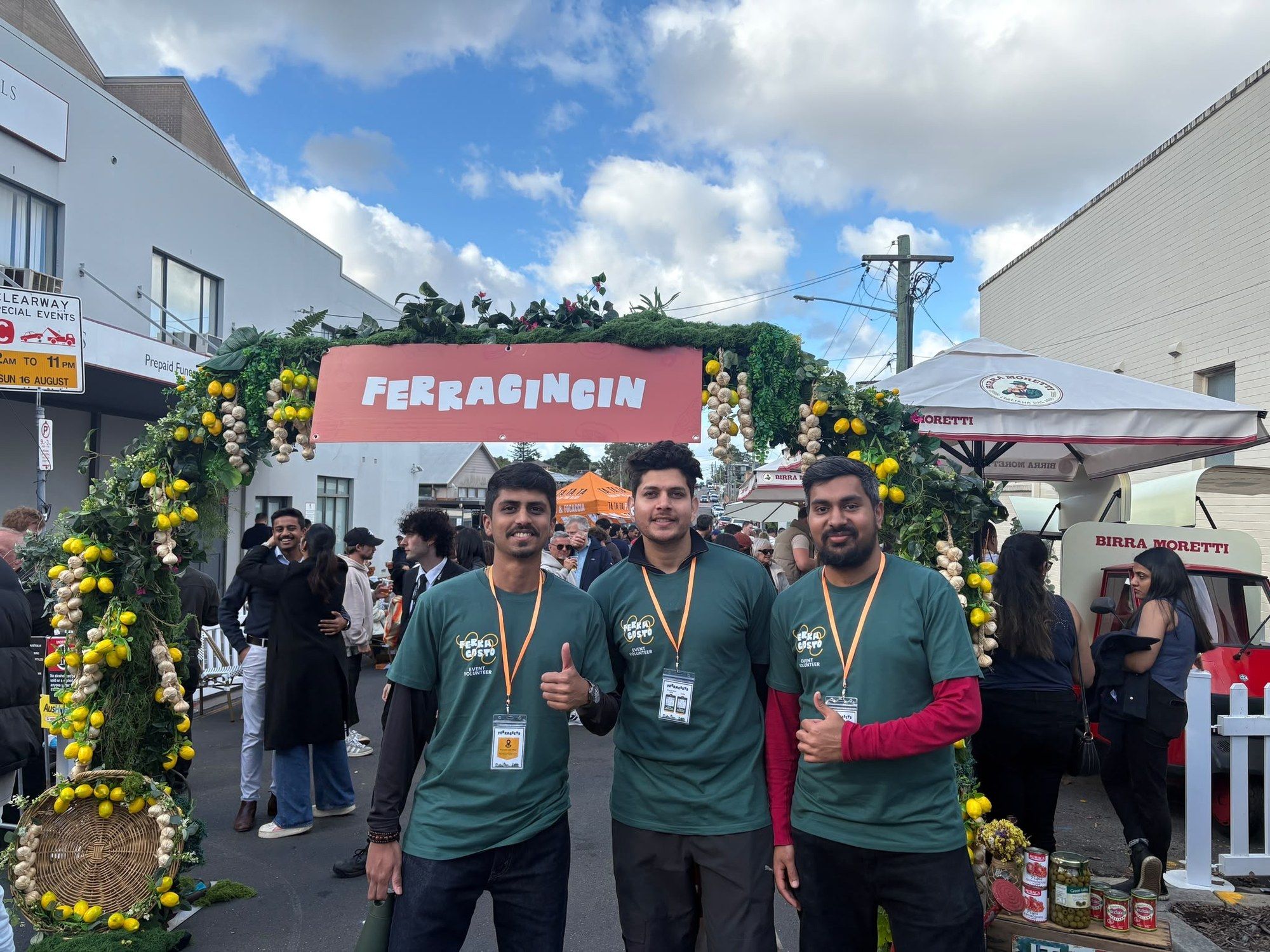 Manish and two volunteers under a lemon-covered Ferragosto archway.