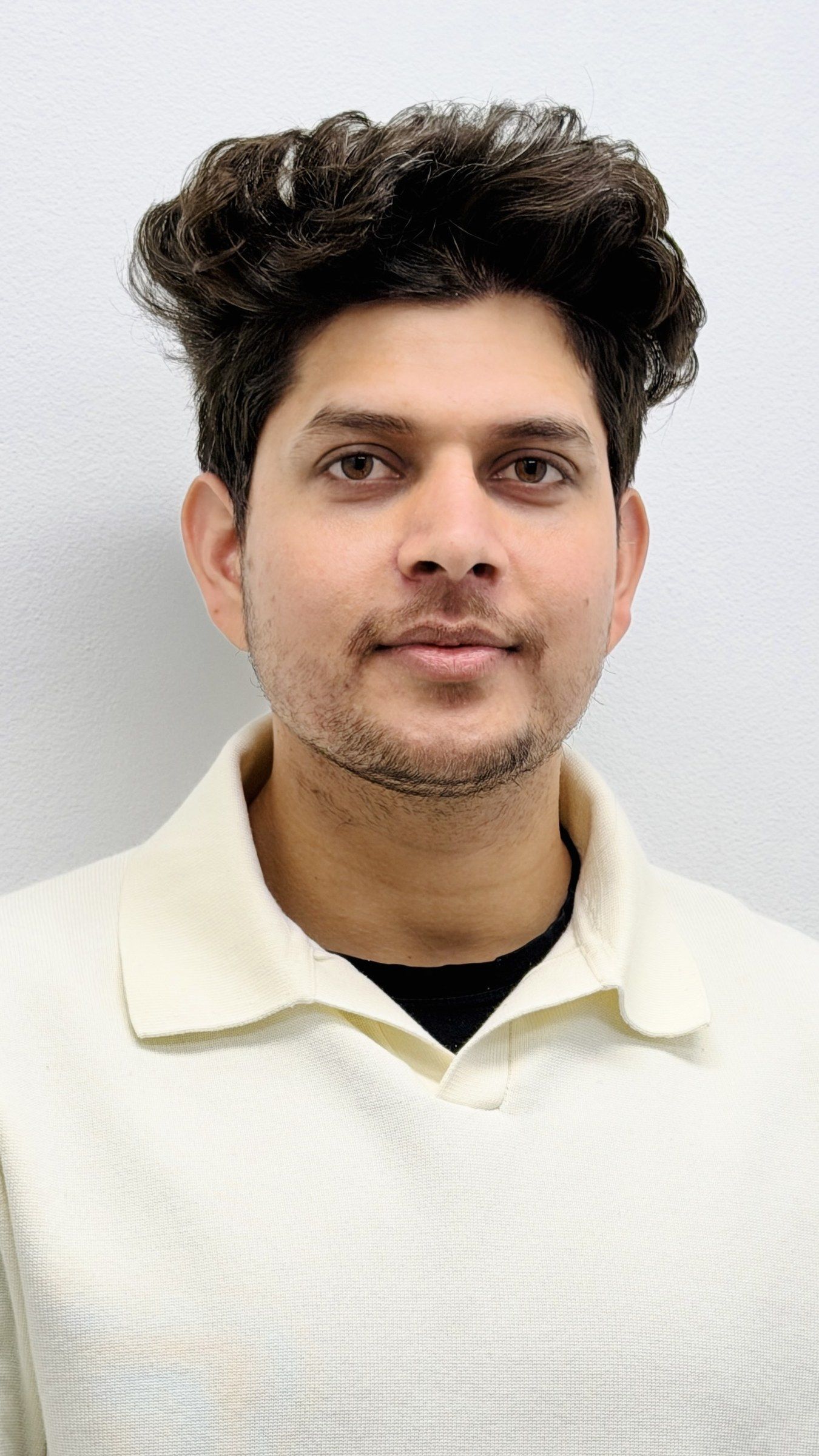 Portrait of Manish in a cream polo shirt against a plain wall.