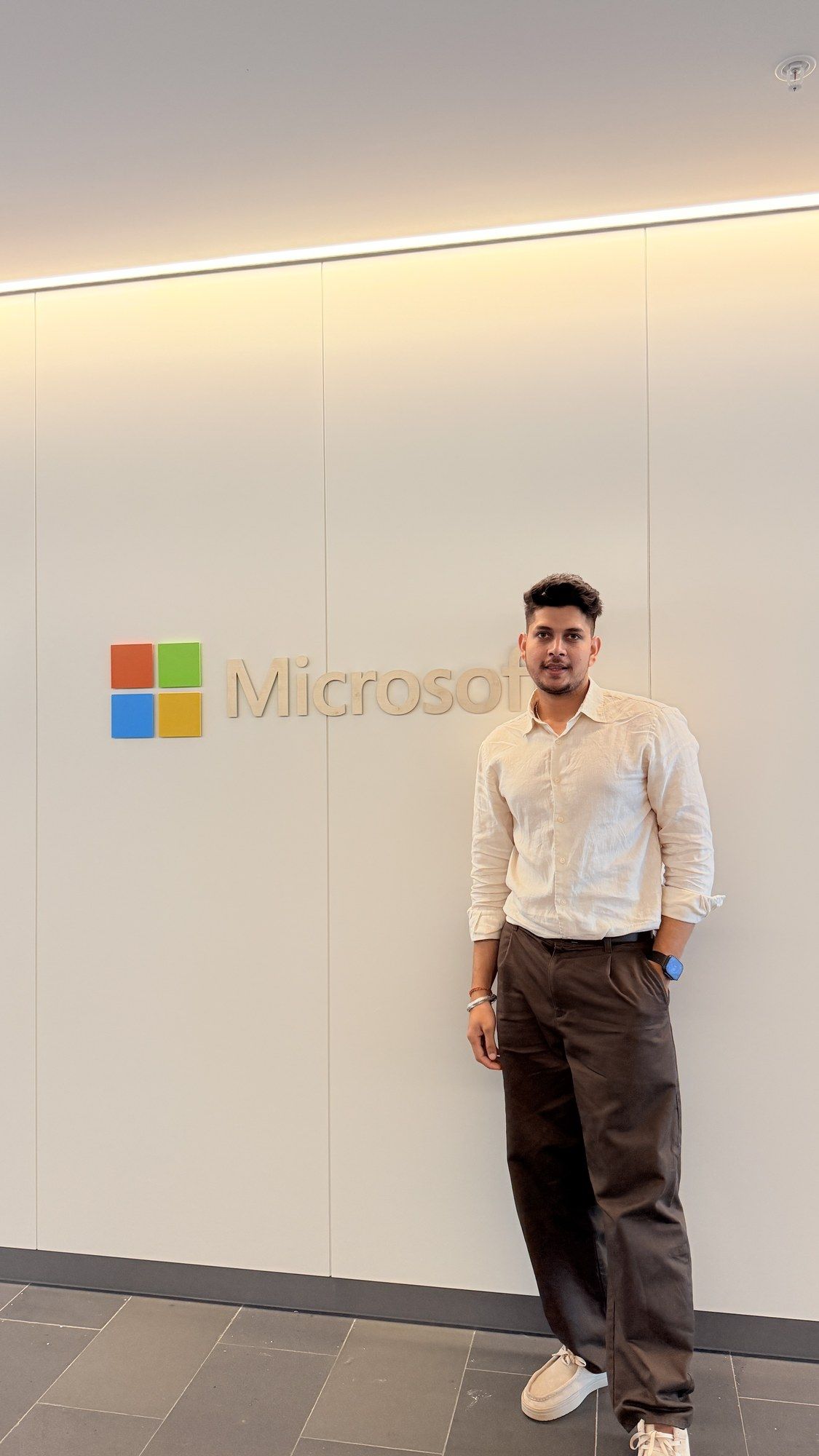 Manish standing beside the Microsoft logo in a white lobby.